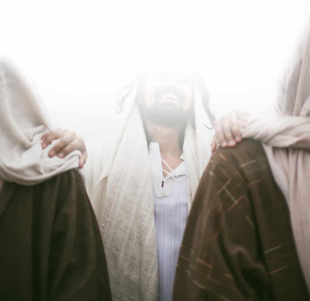 A view of a man laughing with his hands on two individuals shoulders.