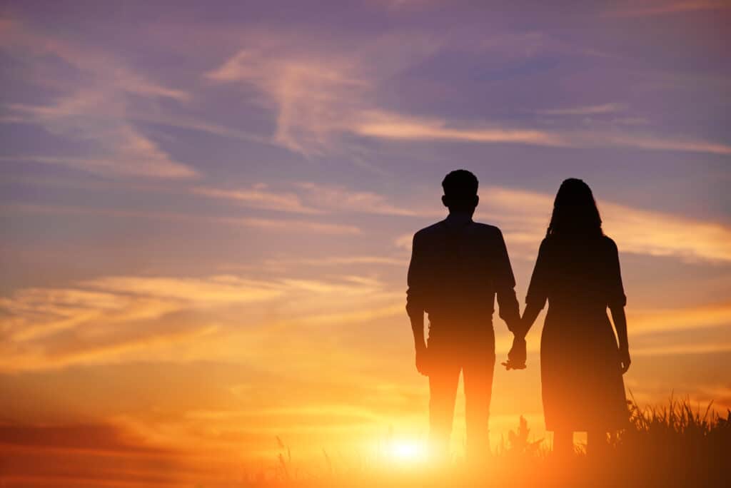 Couple holds hands and view the sunset. 
