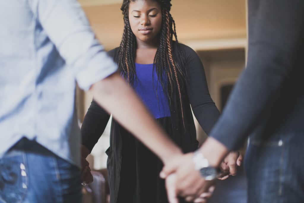 Group standing in a circle holding hands and praying. 