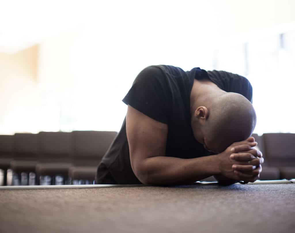 Man kneeling down and praying. 