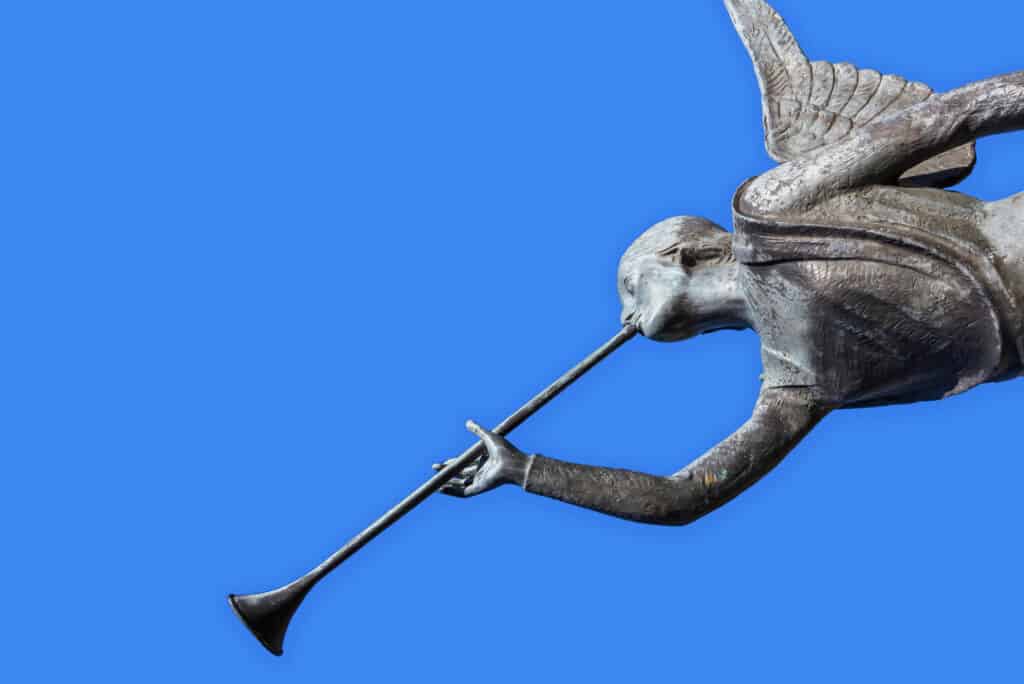 Statue of an angel blowing a trumpet, with a blue sky background.