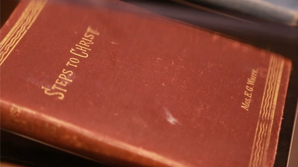 The Steps to Christ book with a brown cover with gold embellishments and writing