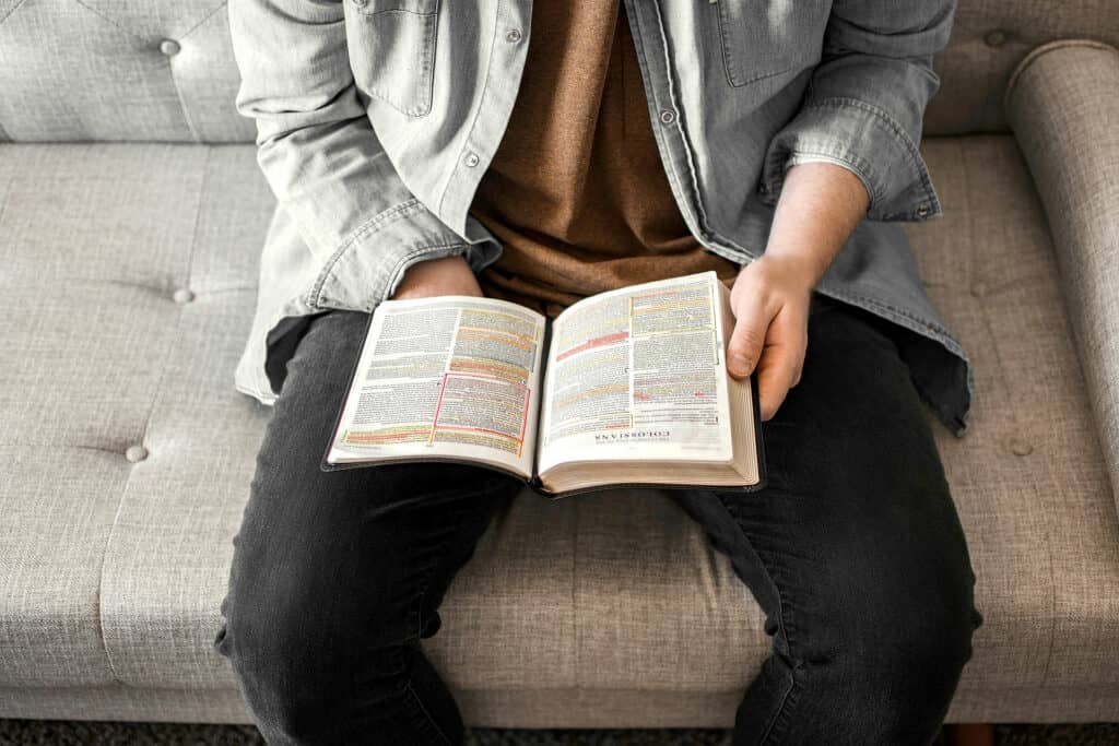 A man holding a Bible open, which is filled with highlighting and notes from him studying the Bible.