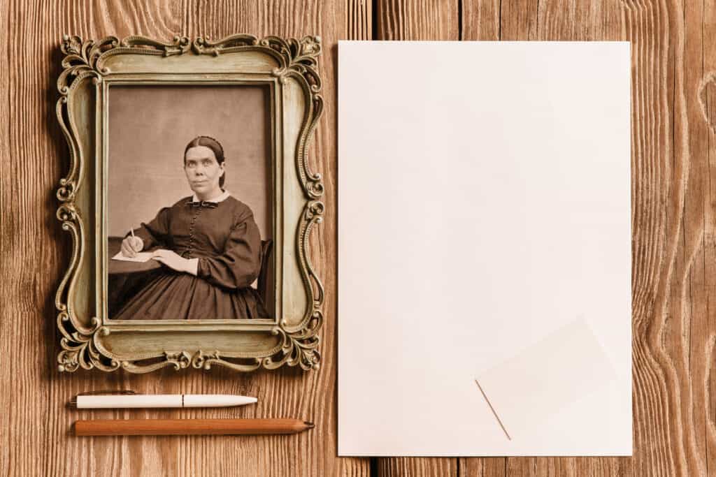 Frame with picture of Ellen White laying on a table with a pen and pencil, next to blank paper.