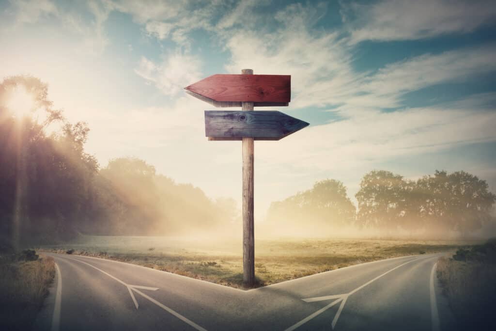 Sign post pointing left and right to two different roads. One towards good and the other towards evil.