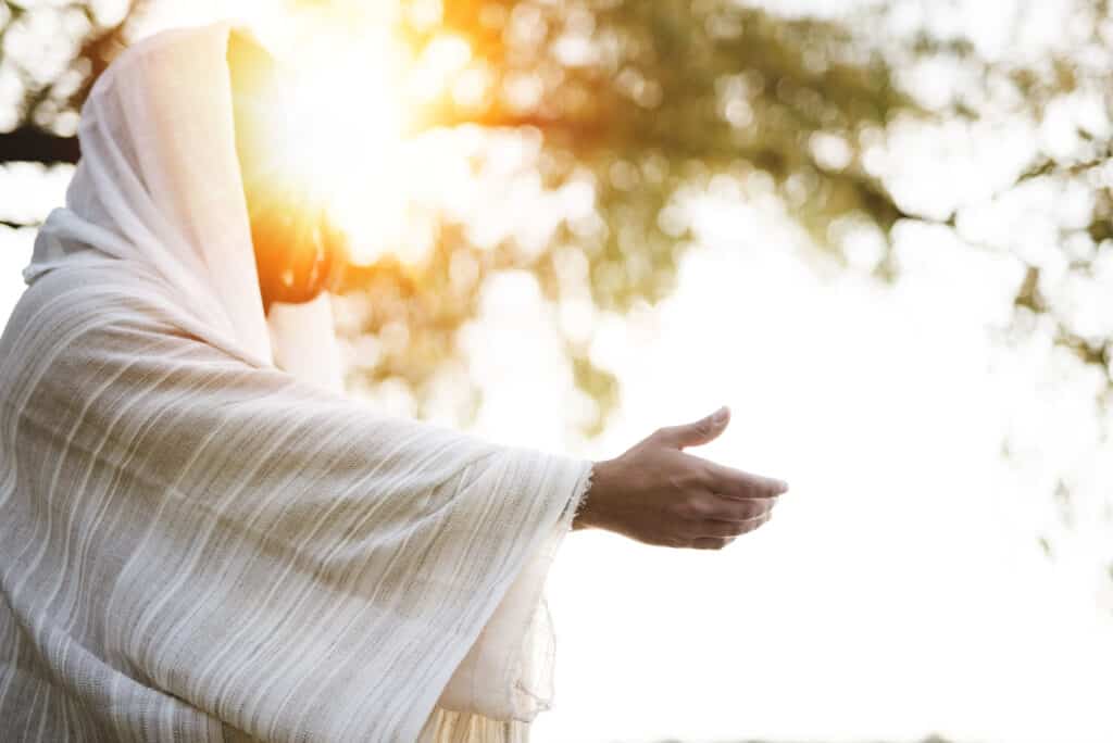 Jesus in a white robe offering a helping hand from evil for anyone who reaches out and asks.