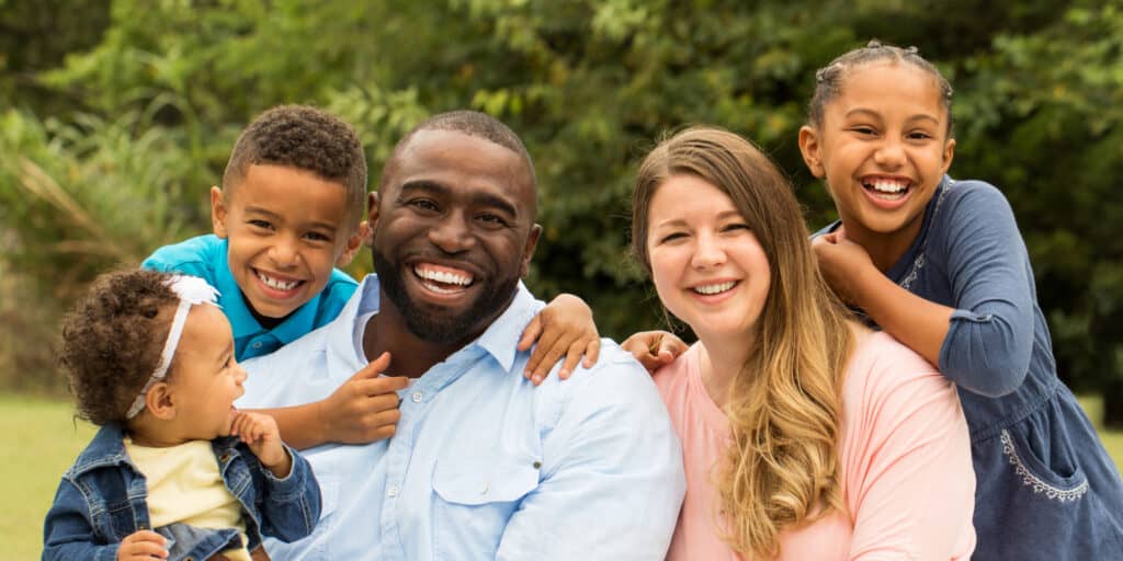 Married couple with their three children smiling together.