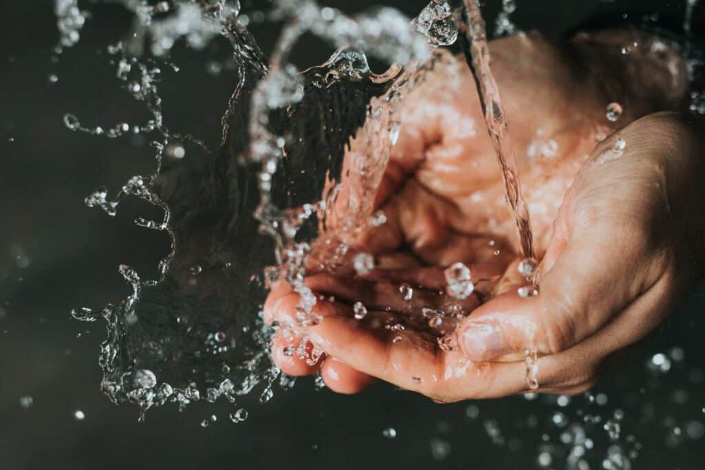 Two hands cupped together to catch fresh clean water falling.