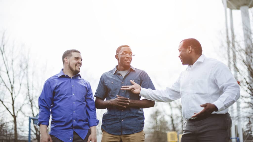 Three men discussing their relationship with Jesus outside.