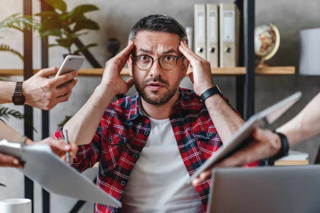 Man overwhelmed by too much technology and screens.