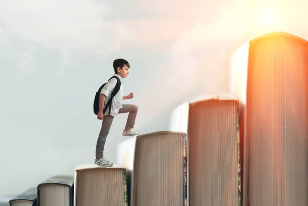 Young male student climbing books as he strengthens his education.