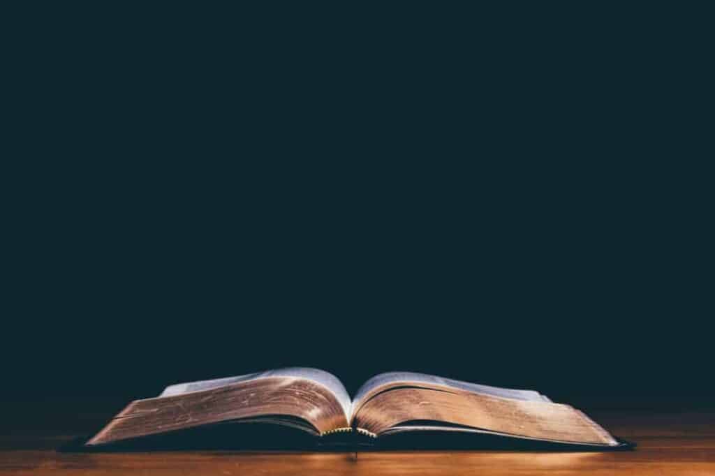 An open Bible laying on a wood table for study.