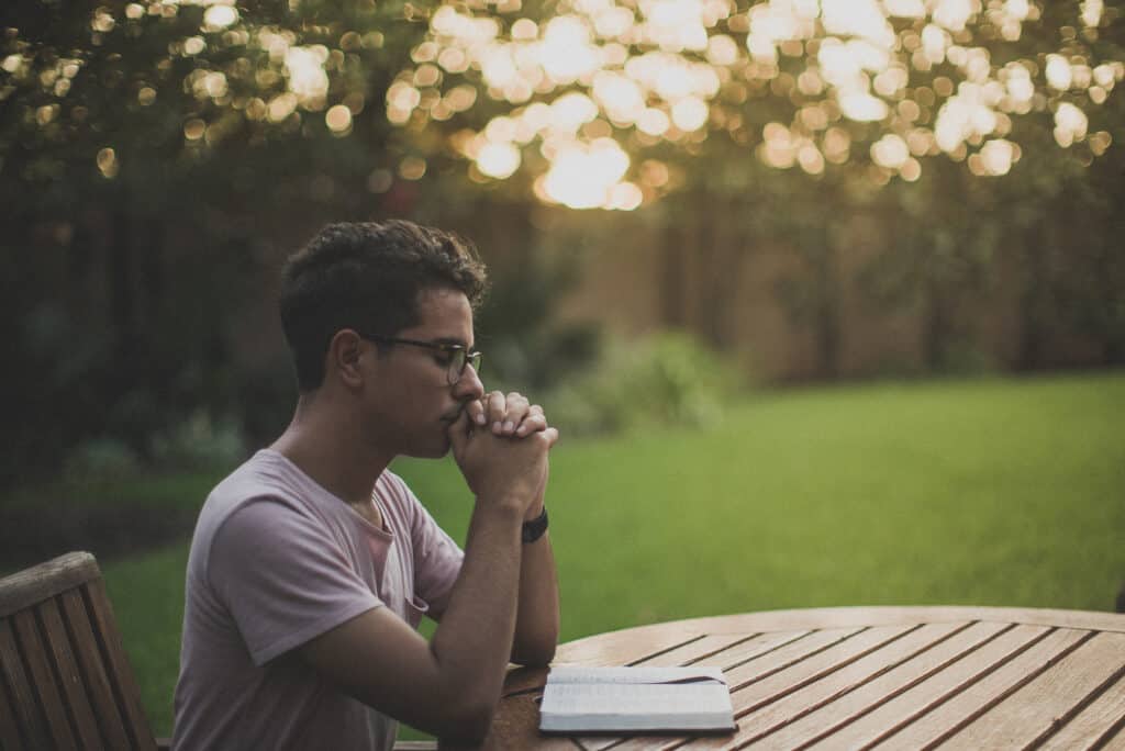 Young man praying a psalm with the Scripture open in front of him.