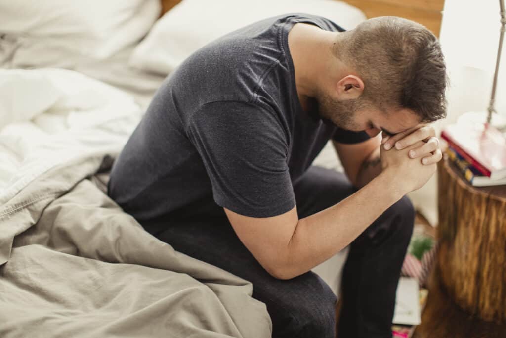 Man giving thanks to God immediately after waking up from his bed.