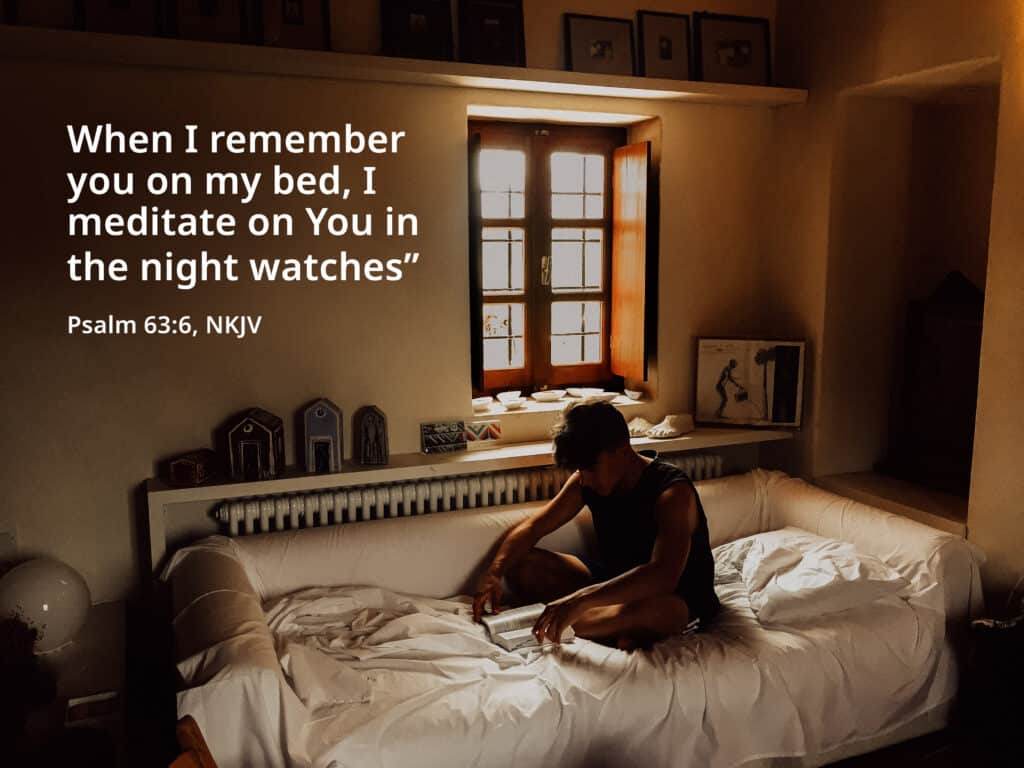 A young boy meditates on God with his Bible while in bed at night time.