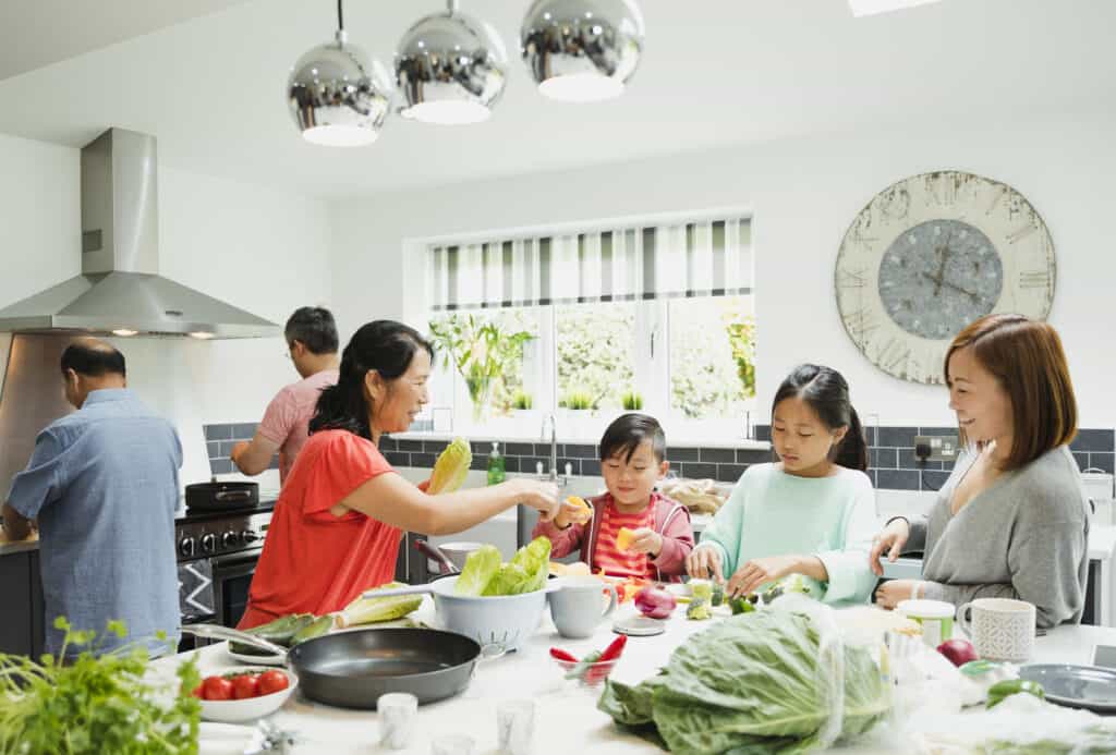 A multi-generational family cooking together using fresh vegetables.