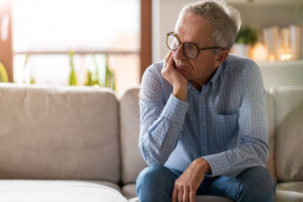 Man Thinking An older man leaning on his hand as he sits on a couch thinking about God.