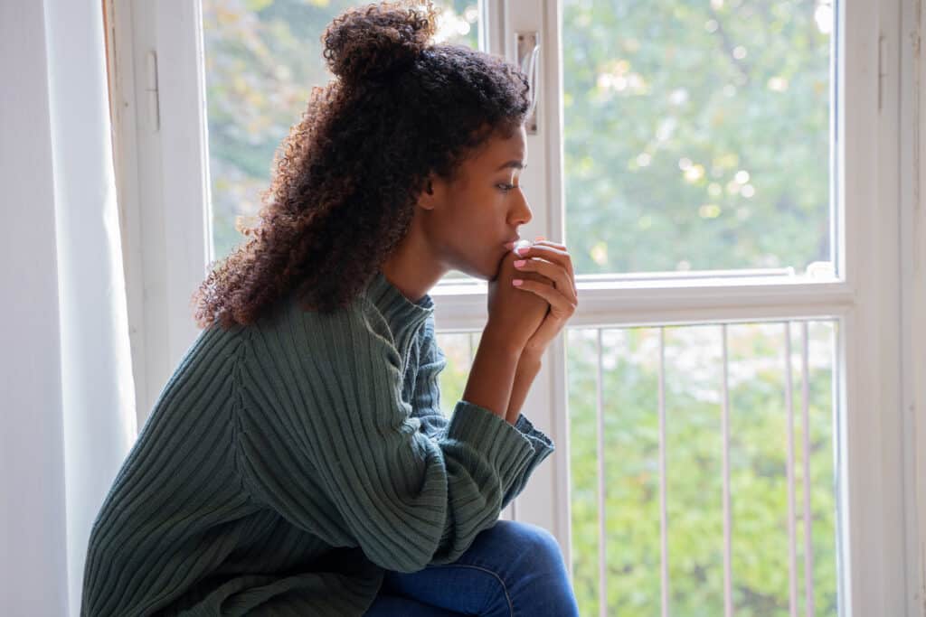 Woman sitting looking troubled by something she can't forget and keeps thinking about.