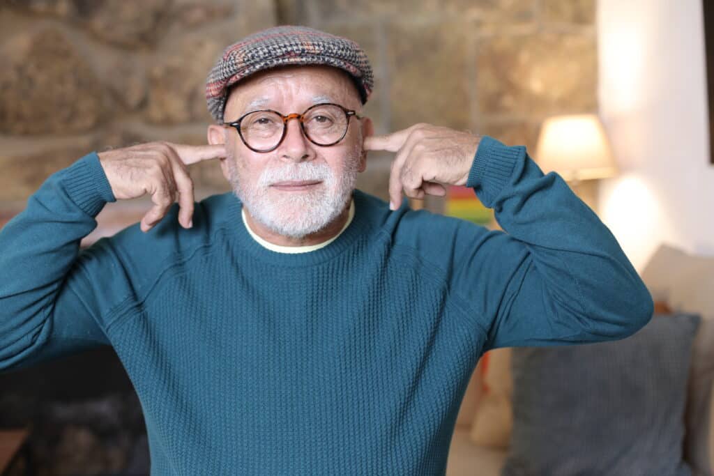 No Ears to Hear An older man plugging his ears so he doesn't have to listen to someone talking.