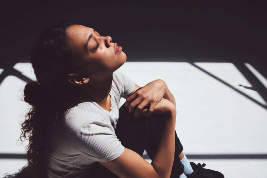 A women sitting on the floor upset, struggling with bitterness from holding a grudge.