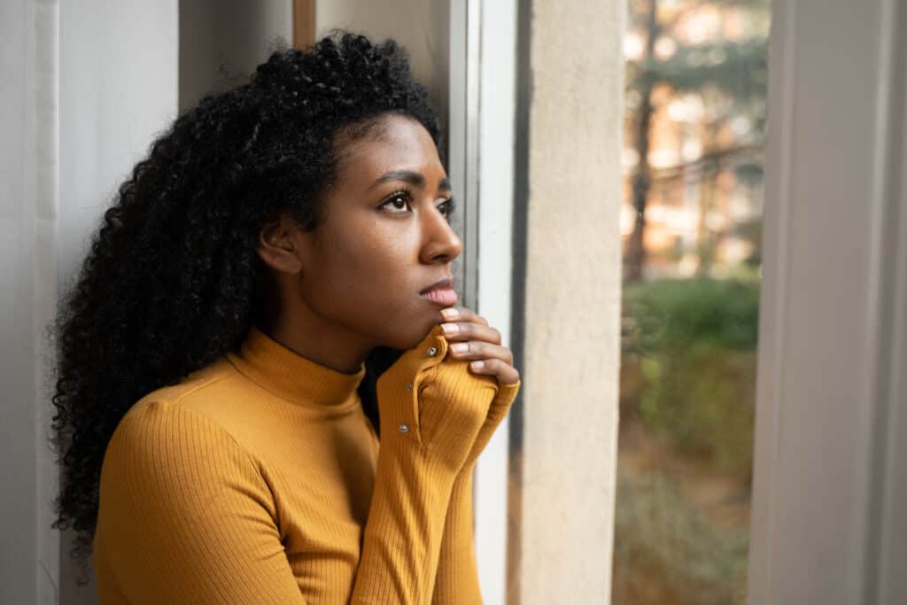 Woman outside looking up as she thinks about what is happening that is burdening her thoughts.