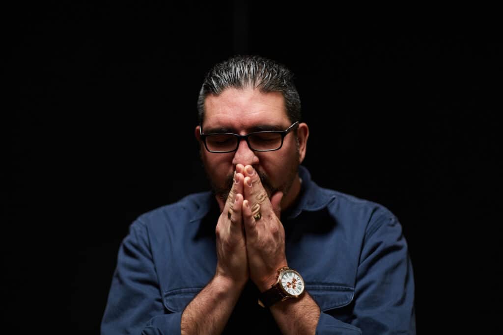 Man praying in a dark room alone, repenting and asking for forgiveness.