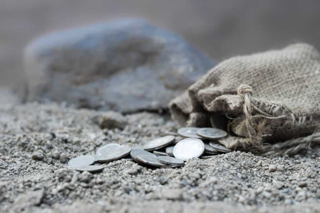 A bag of tax money thrown on the ground spilling silver coins.