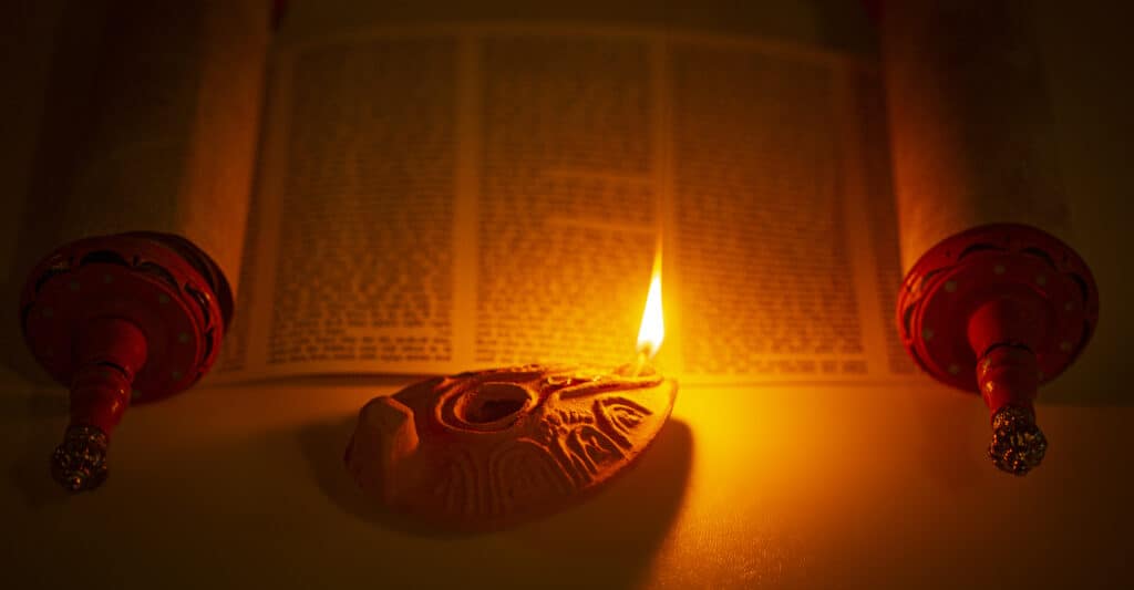 A Hebrew scroll of the Word of God lite by an oil lamp