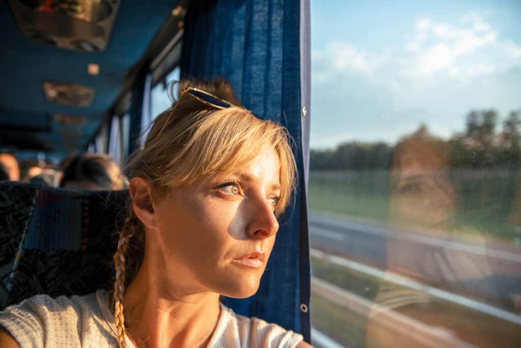 Woman looks out the window while riding a bus.