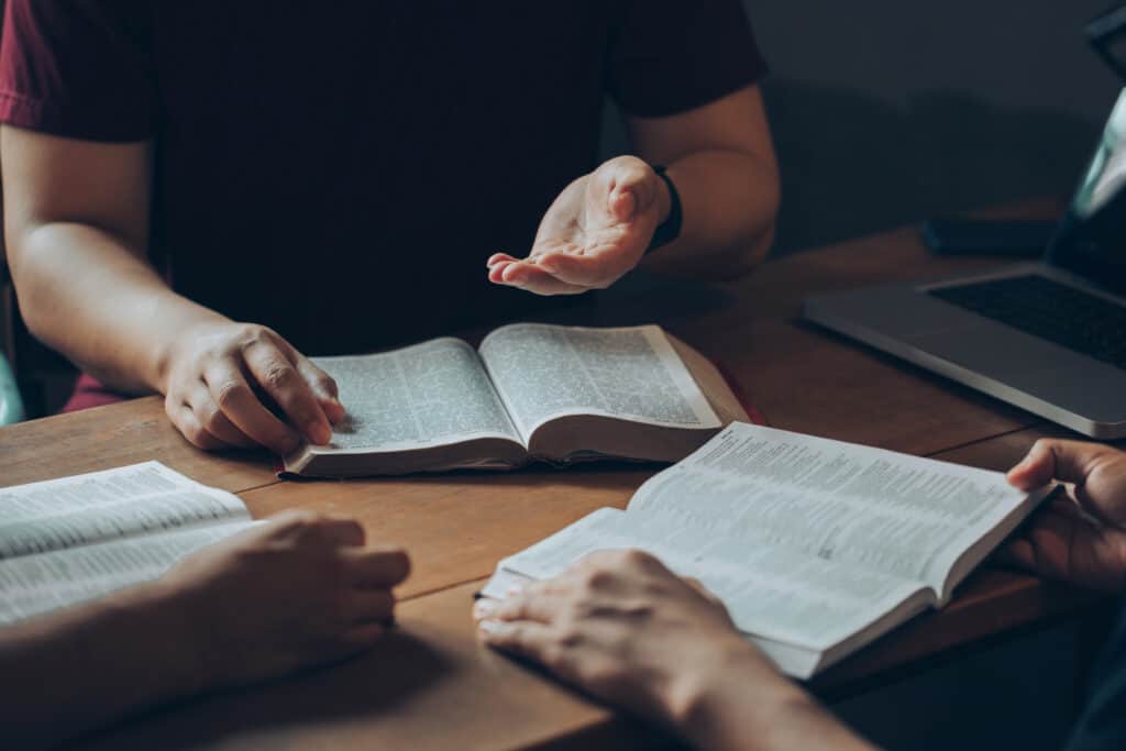 Two people with their Bibles open studying a contradiction of two verses
