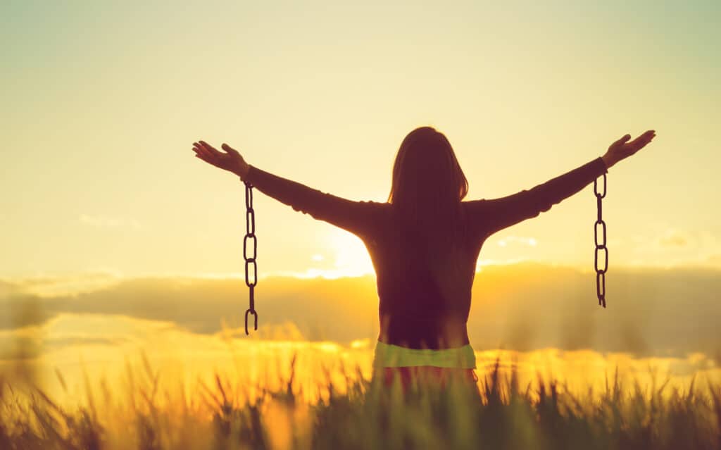 Broke Free from Chains Woman broke free of chains, lifting her arms to praise God, representing how forgiveness releases us from ill will.