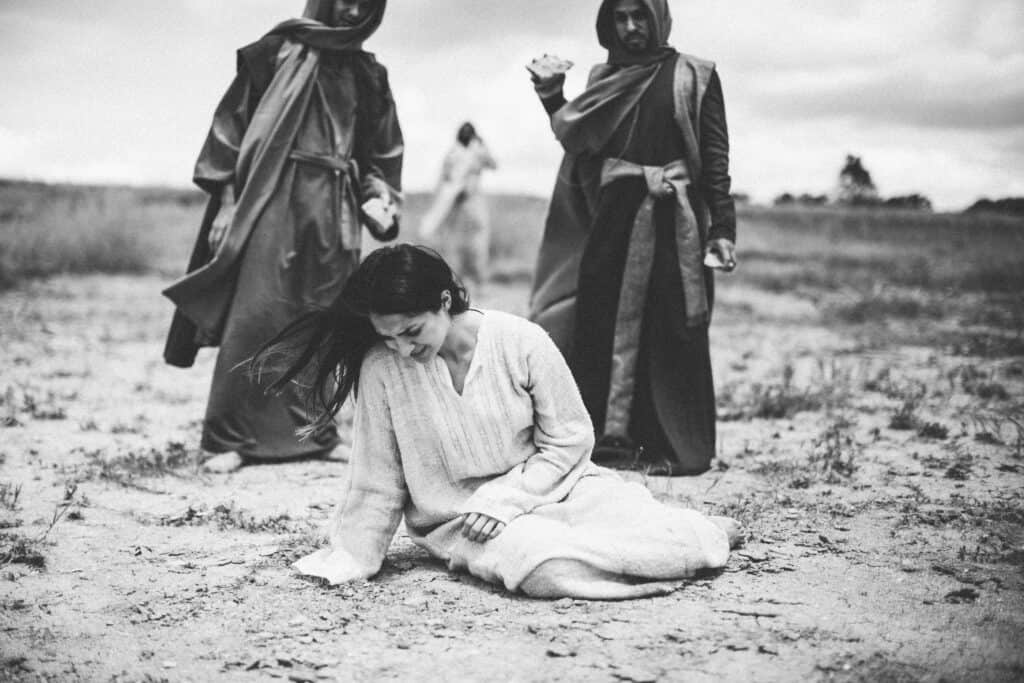 Mary of Magdalene being threatened by two religious leaders with stones, as Jesus forgives her.