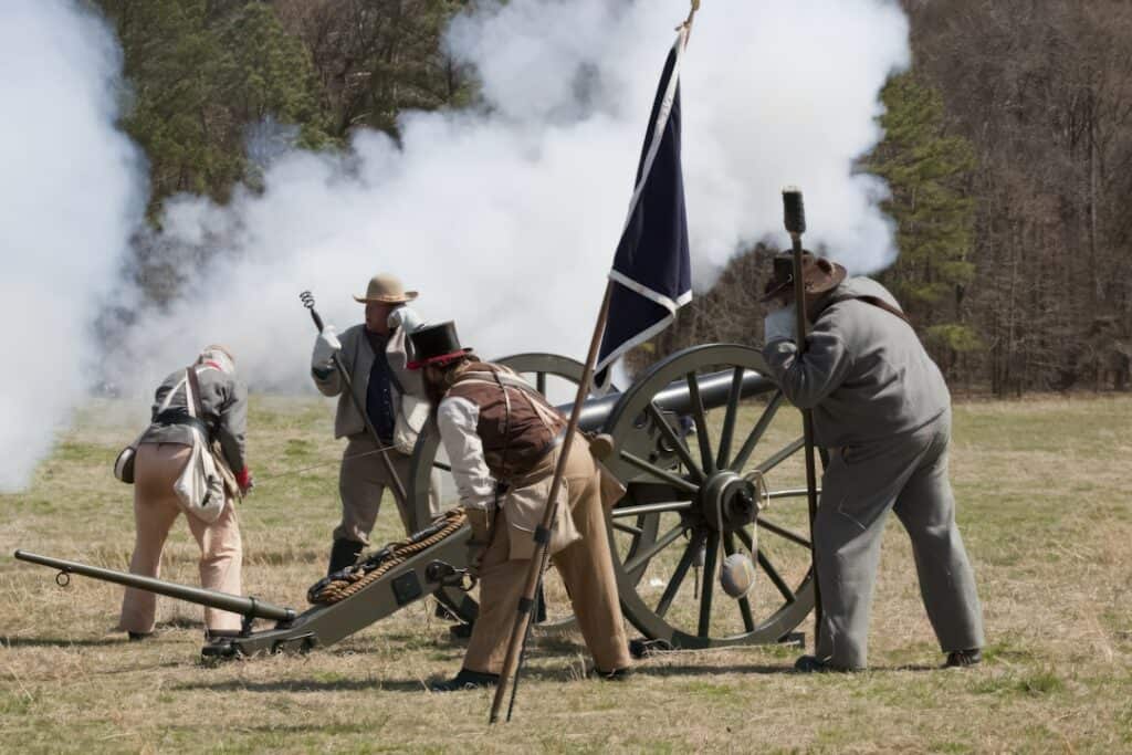 Soldiers in the Civil War work together to fire a cannon in a field